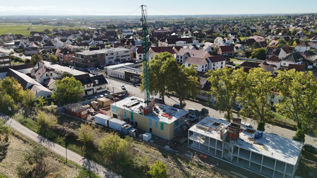 Vue aérienne du chantier Hahnenberg à Châtenois, avec des façades à ossature bois posées sur une partie des bâtiments.